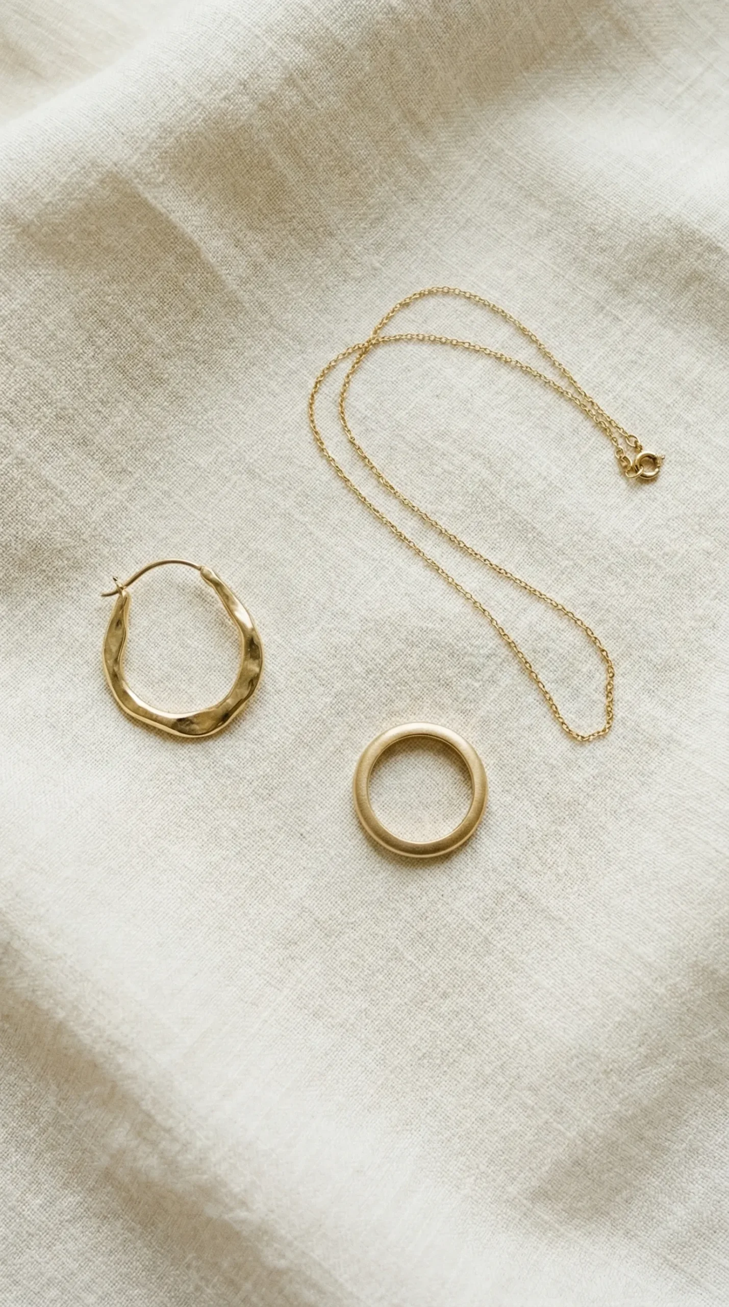 Minimal jewellery for smart casual women's outfits — gold hoops, thin chain and simple rings